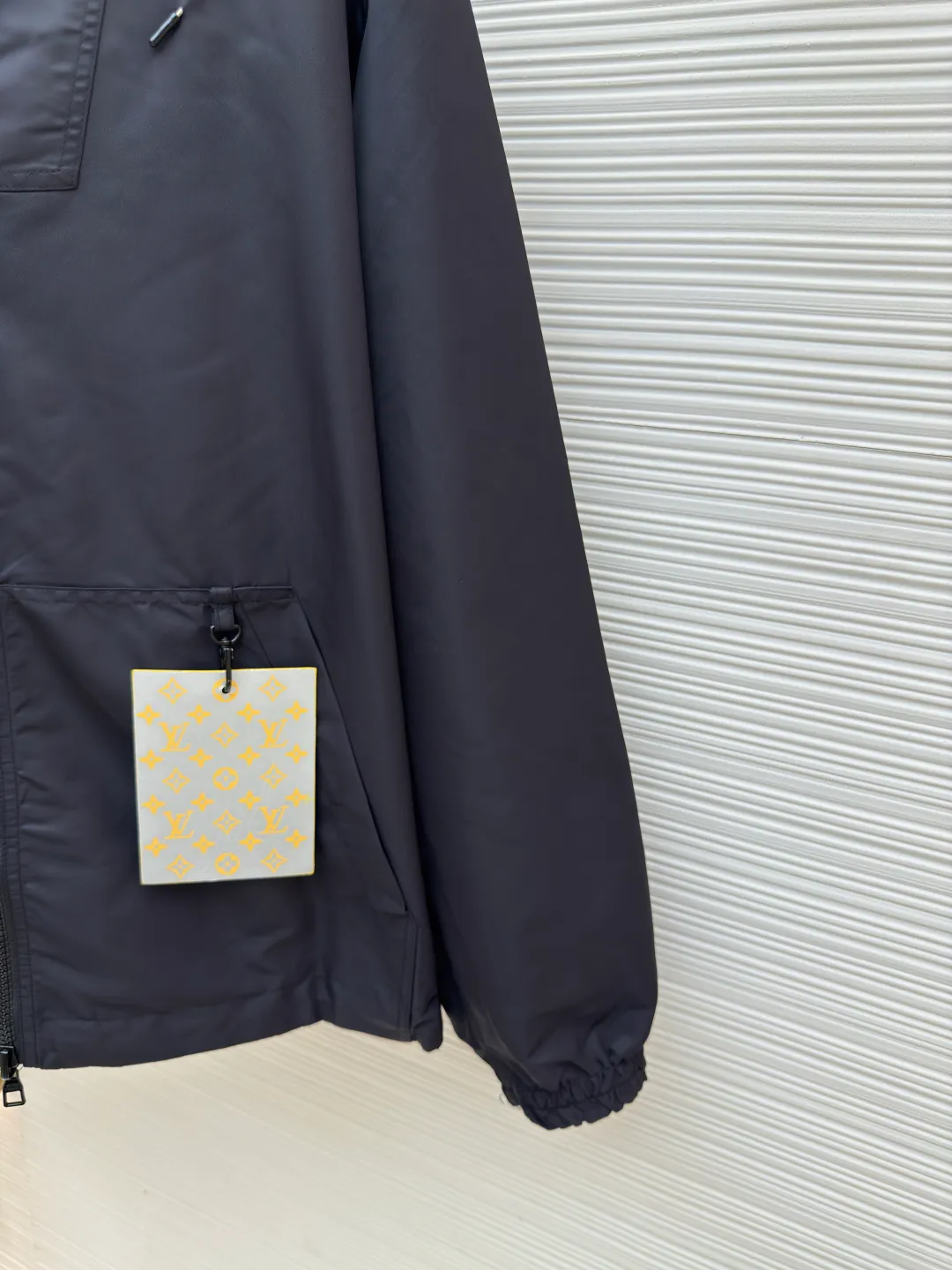 LOUIS VUITTON double-sided windproof pin jacket ●Authentic product: purchased and developed for 22800 ●Item number: 1680472-C55 ●Fabric: polyester fiber fabric ●Technology: jacquard ●Version: fitted version ●Weight: about 565 grams ●Size: 44-46-48-50 ●Description: The solid color fabric is made of nylon encrypted matt twill fabric, and the jacquard fabric on the other side is made of 50D nylon yarn-dyed jacquard fabric. The solid color front panel is laser-burned, hand-made of white copper, with a triangle pin with logo and glossy finish. The front panel pocket uses a hardware keychain to hang a folding clothing tag, and the jacquard letters on the front chest placket are made of single-piece flowing pure It is cut by hand to restore the flower, and all the pieces are numbered. The pockets are also cut with the restored flower number. The fabric is relatively light and silky, and it takes time to cut accurately. The front and center are equipped with a double-circulation puller 5# orbital zipper. The hem and the hood are worn with spiral elastic ropes with ring anti-slip buckles, square pig nose buckles with logo, and all holes are punched with hardware and logo on the cloth-colored cornrows.